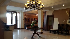 A spacious lobby with a large chandelier, a reception desk, and a seating area with a floral arrangement. - Hotel Savera (Chatworth)