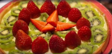 Una tarta de frutas con fresas y rodajas de kiwi por encima.