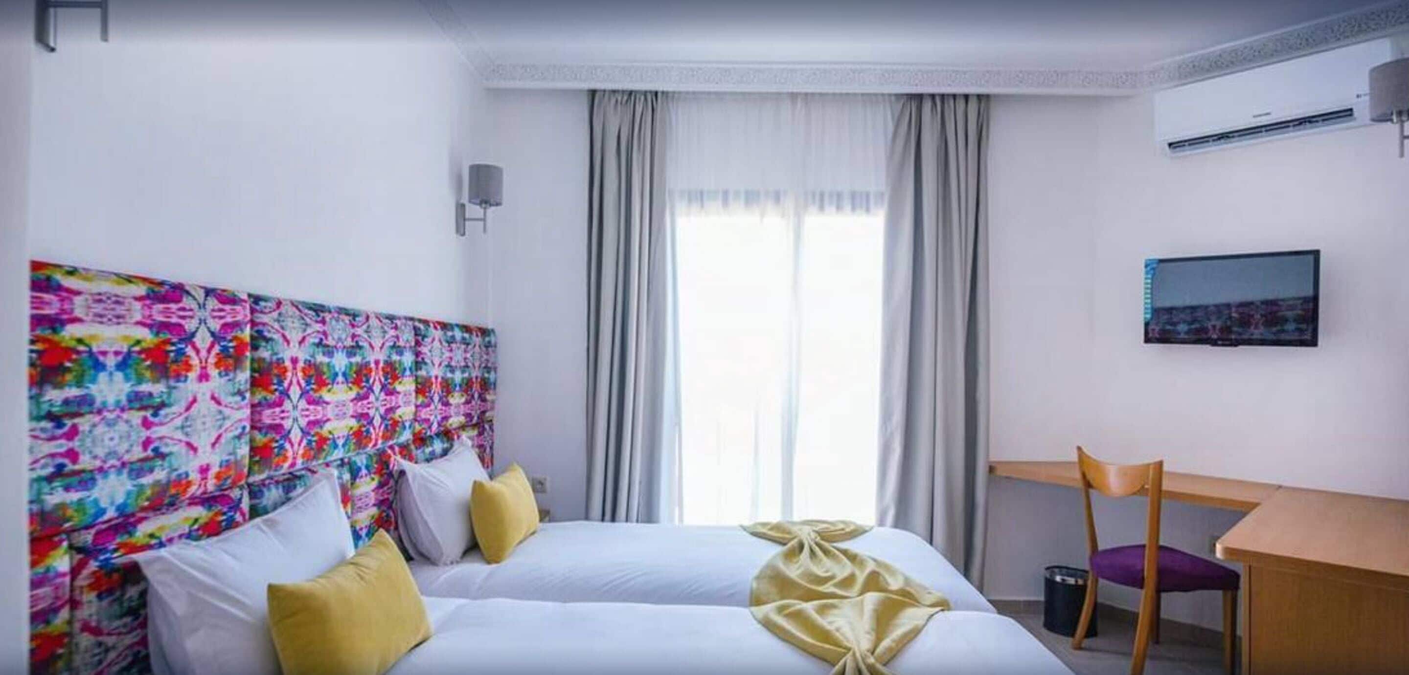 A hotel room with a bed, a desk, and a chair.