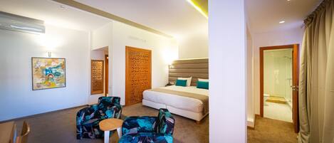 A hotel room with a bed, two armchairs, a small table, and a shower area.