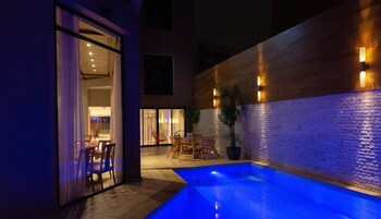 An outdoor pool area with a wooden wall, seating, and a potted plant.