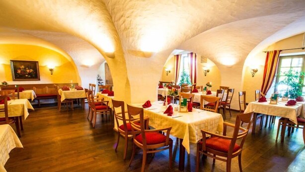 A restaurant with wooden tables and chairs, white tablecloths, and red cushions. - Brauerei-Gasthof-Hotel Laupheimer (Westerheim)