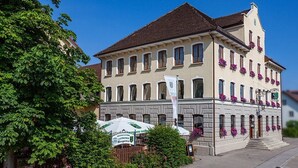 A historic building with a balcony adorned with flowers, a sign indicating a restaurant, and a white umbrella. - Brauerei-Gasthof-Hotel Laupheimer (Westerheim)