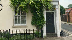 A two-story building with a white facade, a black door, and a black fence. - Ourhaus (Beverley)