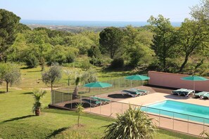 Una piscina al aire libre de temporada, sombrillas, tumbonas