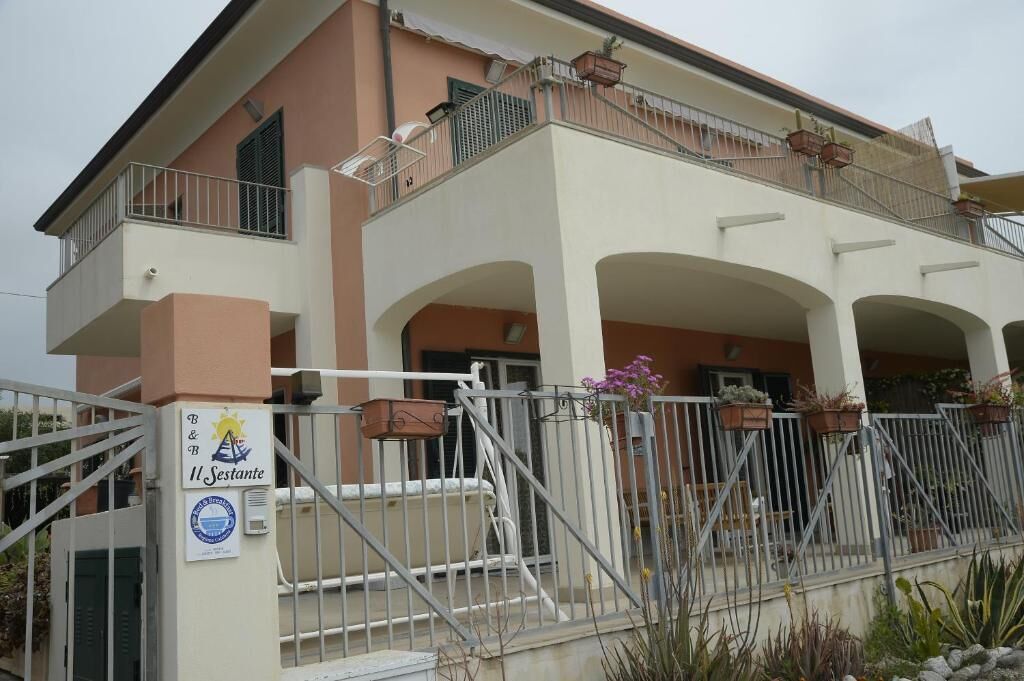 A two-story building with a gated entrance, balconies, and outdoor seating areas.