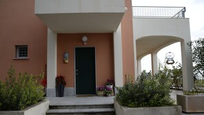 Un edificio con puerta verde, escalones que llevan a la entrada y macetas con plantas.