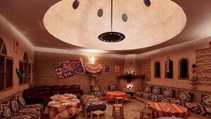A cozy, rustic room with a fireplace, multiple seating areas, and a large circular ceiling feature.