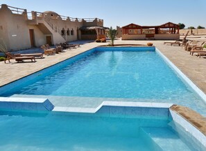 Relax by the pool surrounded by lounge chairs and a shaded pavilion.