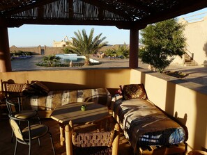 Relax in a serene outdoor space with a pool view, surrounded by palm trees and a covered pergola.