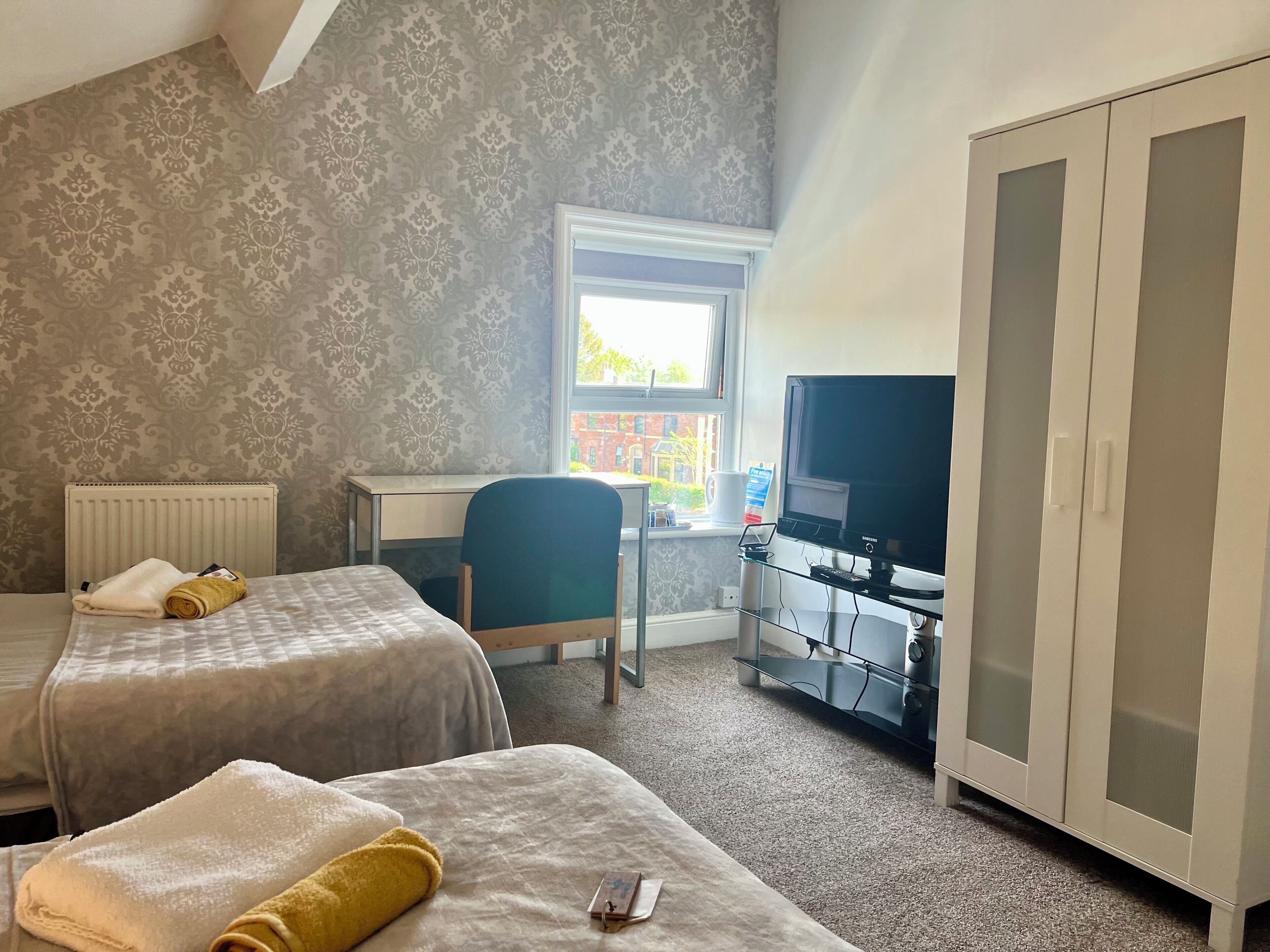 A hotel room with two beds, a desk, a television, and a wardrobe.