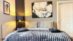 A bedroom with a large bed, a radiator, a wall-mounted lamp, and a framed picture. - St Andrews House Hotel (Preston)