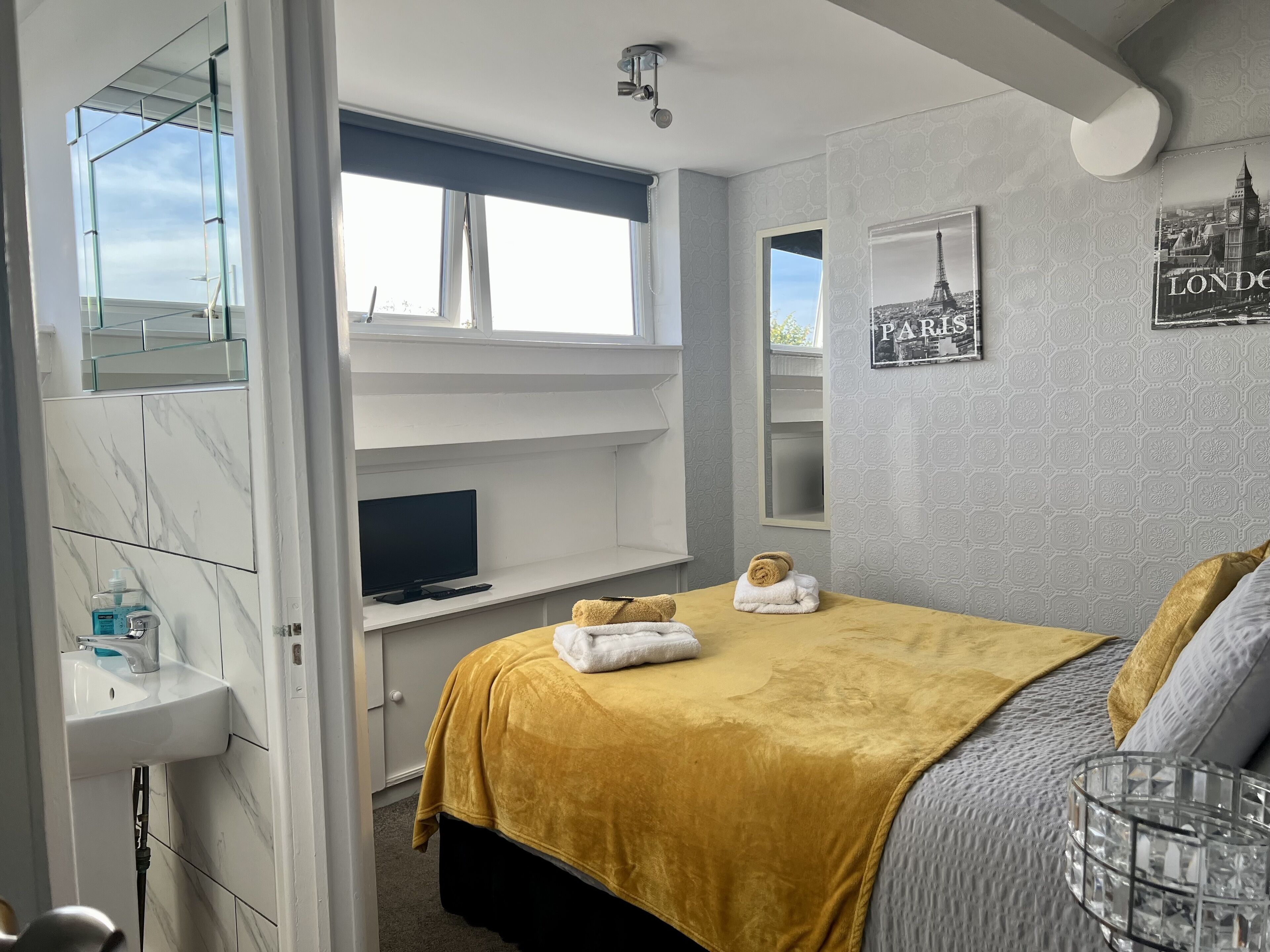Una camera da letto con un letto, una televisione, uno scaffale, una finestra e un bagno.