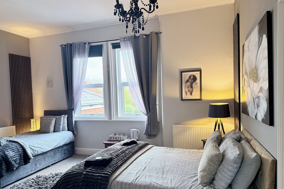 Une chambre avec deux lits, un lustre, un radiateur et des œuvres d’art accrochées aux murs.