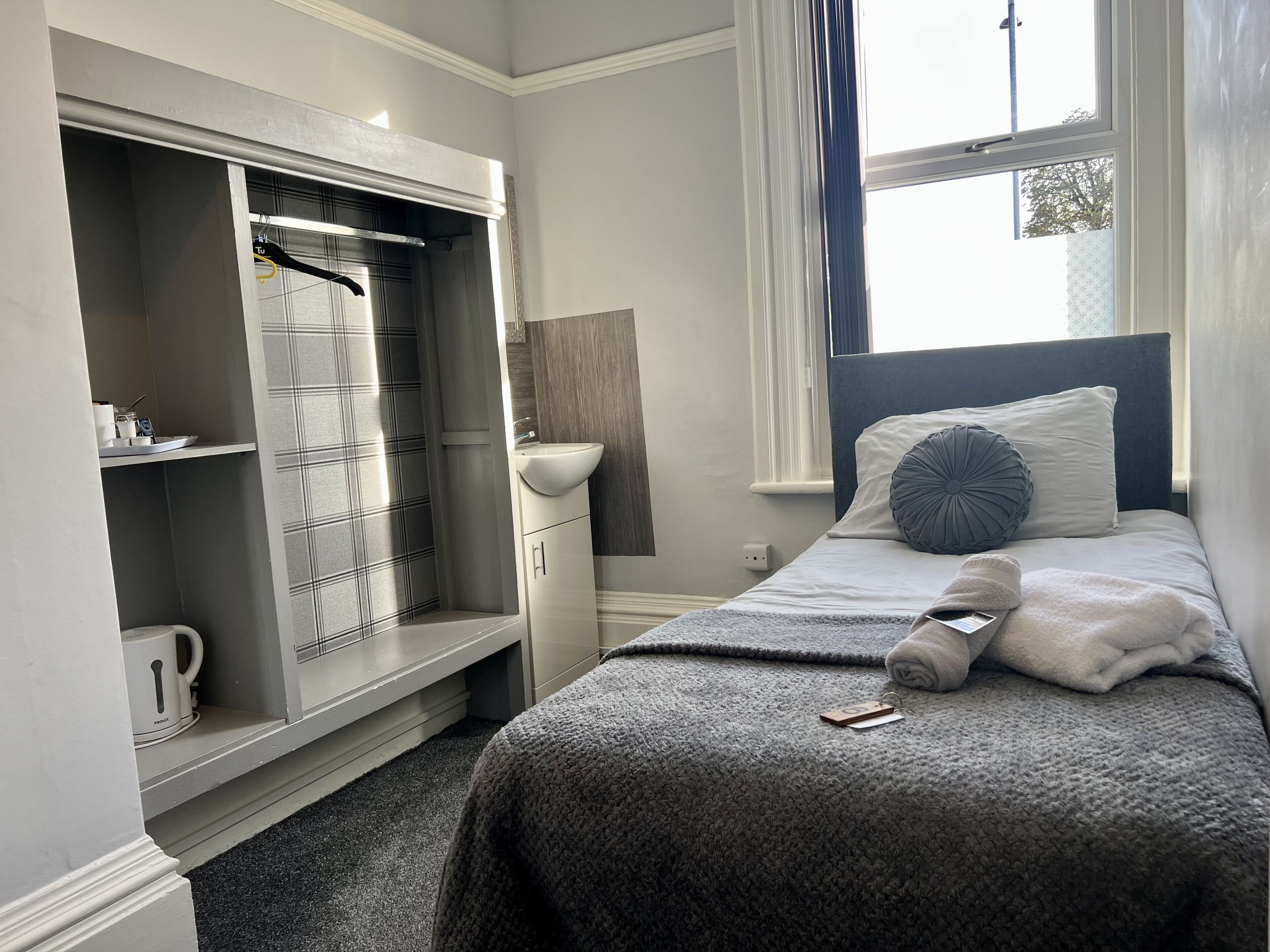 A bedroom with a bed, a bedside table, a wardrobe, and a window.
