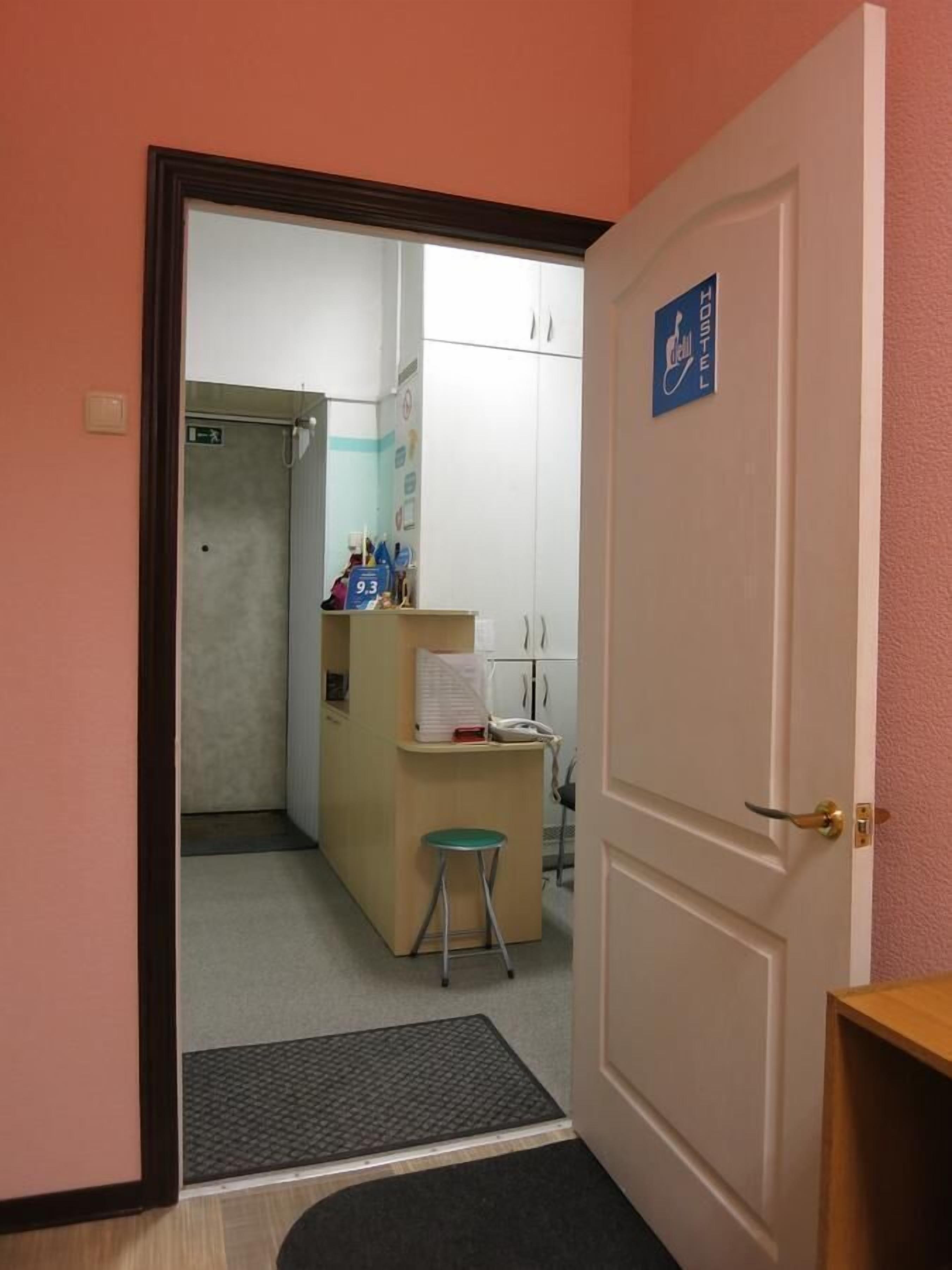 A hotel room with a door leading to a bathroom, a desk with a telephone, and a small stool.