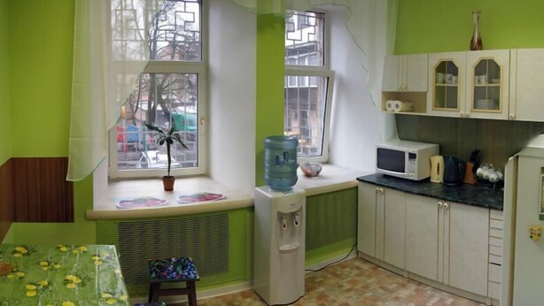 A compact kitchen with a window, a radiator, a microwave, and a water dispenser. - Hostel Delil (Kyiv)