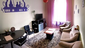 A living room with a sofa, chairs, a TV, a table with a vase, and a wall decoration. - Hostel Delil (Kyiv)