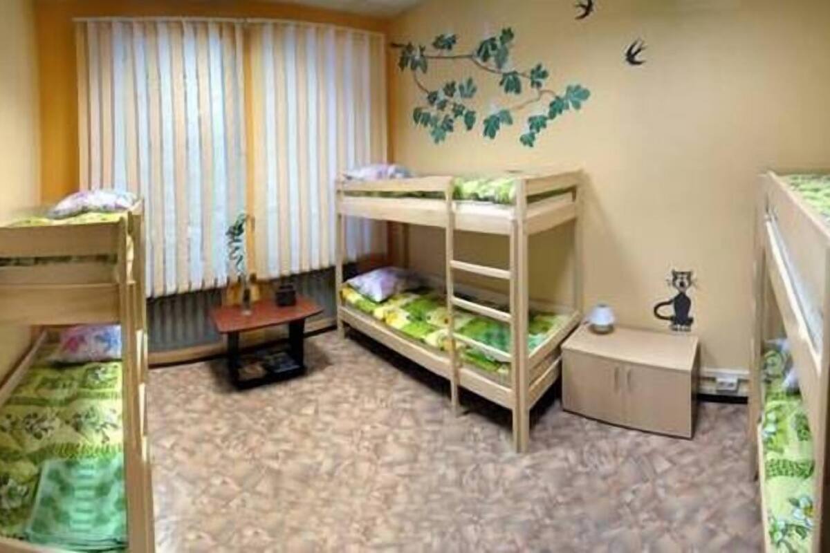 Quarto infantil com beliches, uma mesinha e um enfeite de parede.