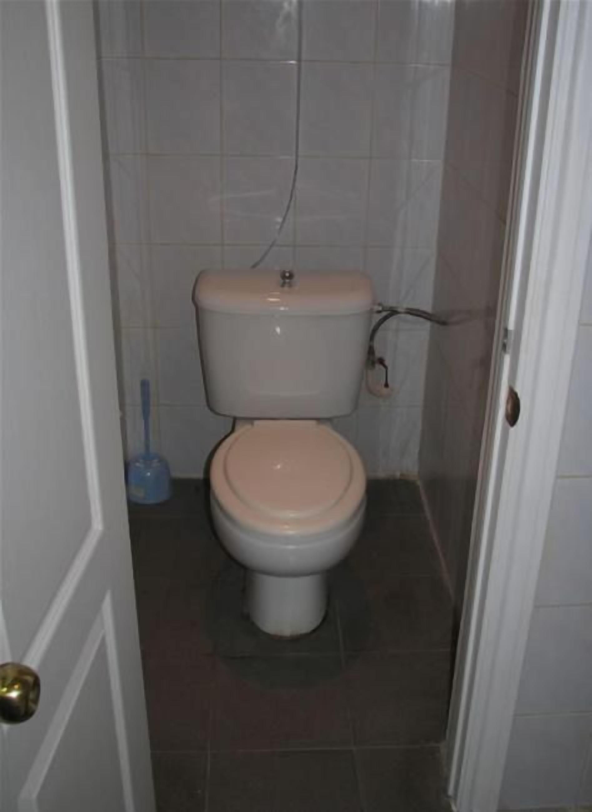 A small, enclosed bathroom with a toilet, a visible pipe, and a door.