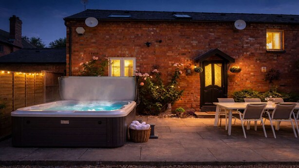 A brick building with a hot tub, outdoor seating, and a door with lights. - Falstaff Cottage - Sleeps up to 5 - Stratford upon Avon (Stratford upon Avon)