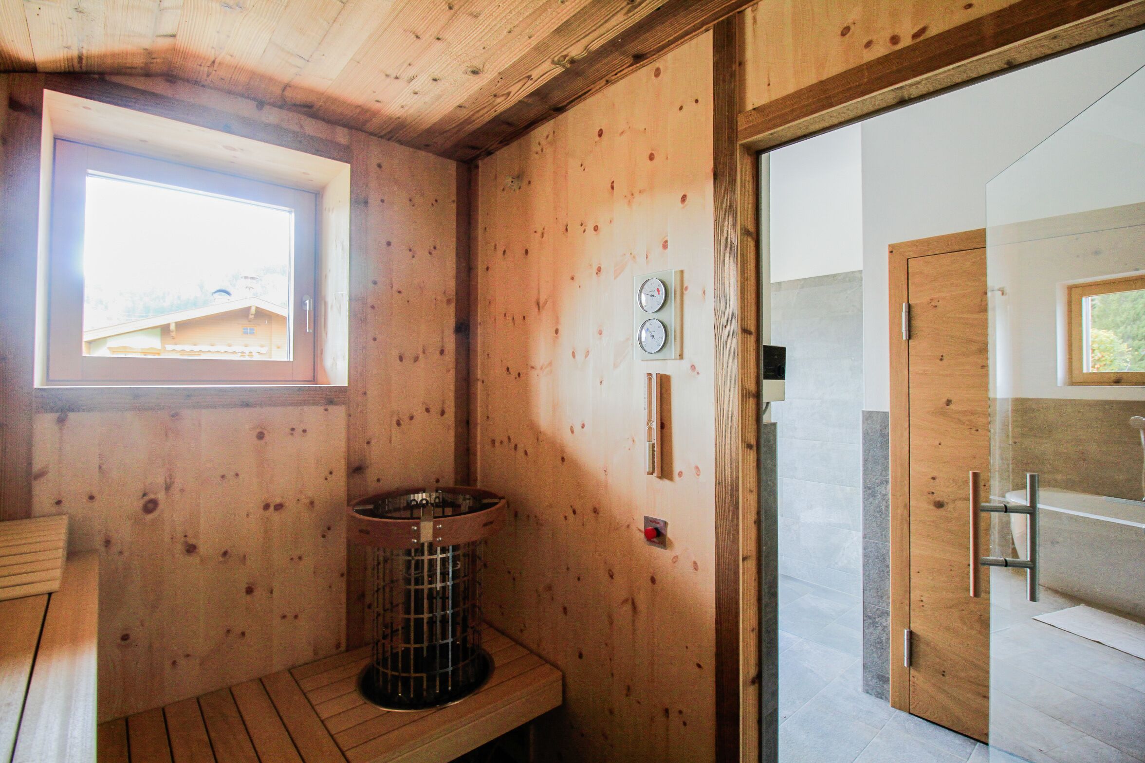 A wooden cabin bathroom with a window, a sink, and a shower area.