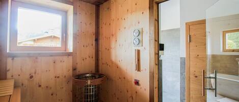 A wooden cabin bathroom with a window, a sink, and a shower area.