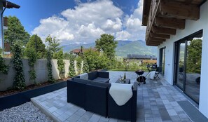 A patio with outdoor furniture, a grill, and a view of mountains.