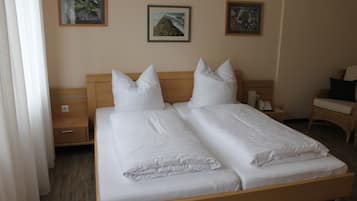 Una cama doble con ropa de cama blanca, un cabecero de madera y dos mesitas de noche con lámparas.