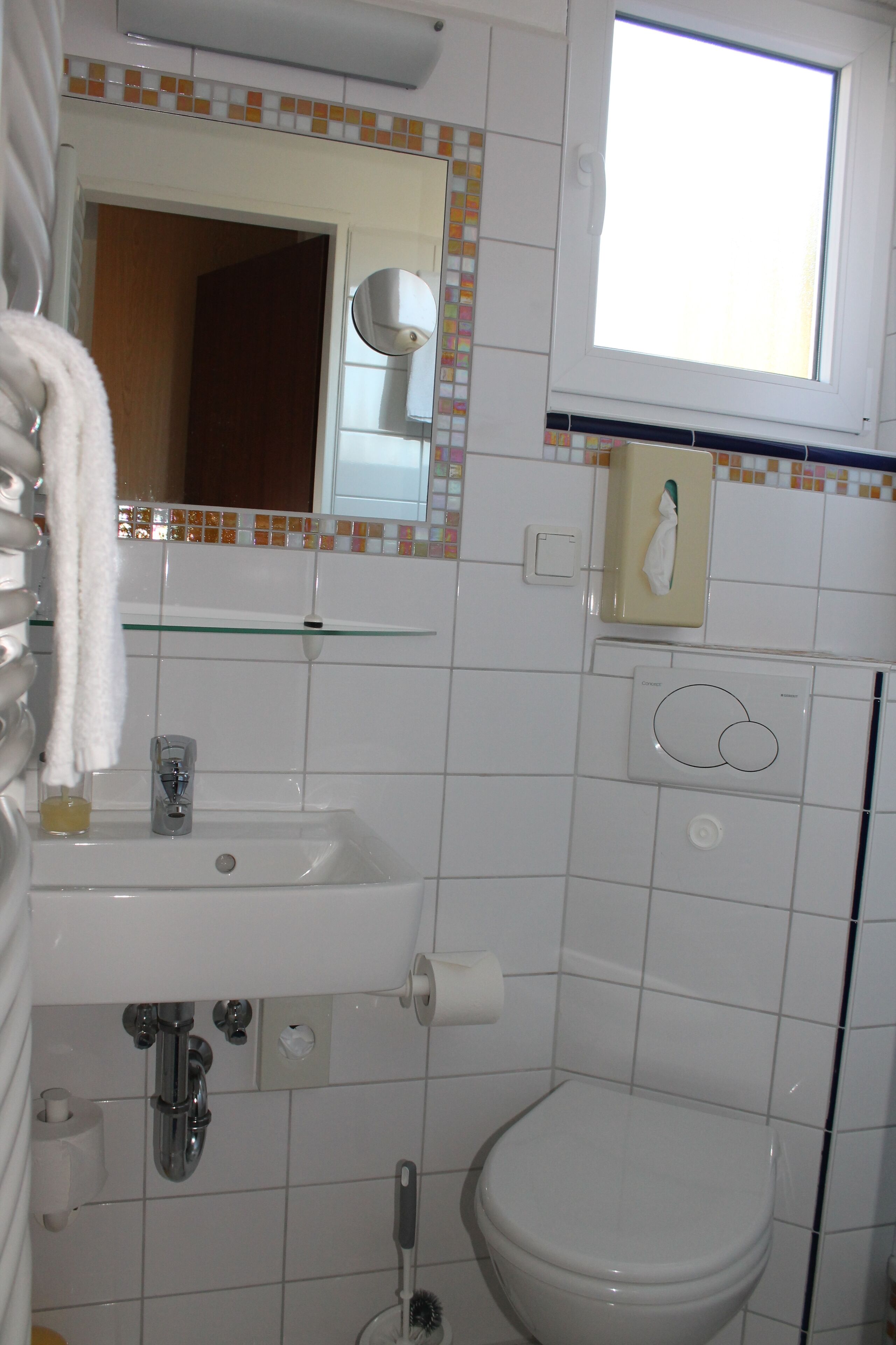 Une salle de bain avec un lavabo blanc, des toilettes, un miroir et une fenêtre.