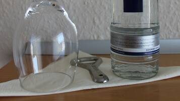 A clear glass bottle and a wine glass on a white cloth.