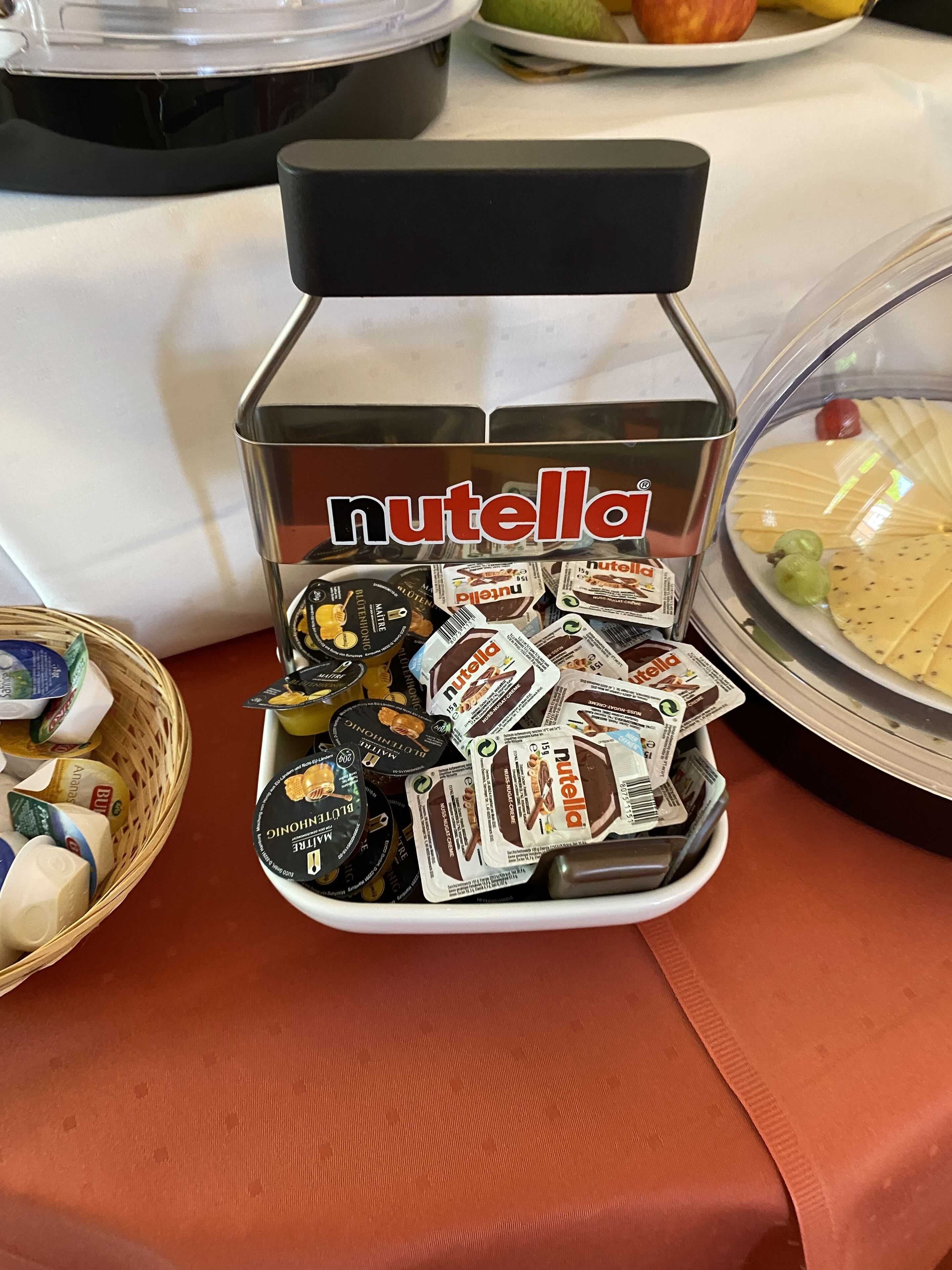 A Nutella dispenser filled with various Nutella flavors on a table.