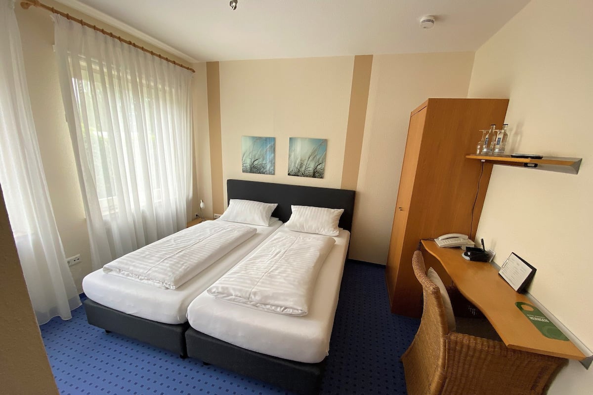 Une chambre d’hôtel avec un lit double, un bureau avec un téléphone et deux tableaux accrochés au mur.