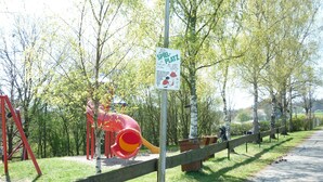 Ein Spielplatz mit einer roten Rutsche und einem Schild, auf dem 'Spielplatz' steht.