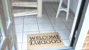 Eine Fußmatte mit der Aufschrift 'WELCOME GOODBYE' auf einem Fliesenboden.