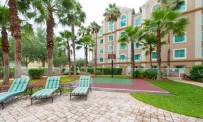 A courtyard with palm trees, a basketball court, and lounge chairs. - Charming Newly Renovated Unit 1 Mile to Disney and Great Shopping (Orlando)
