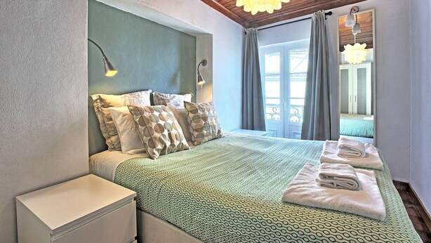A hotel room with a bed, bedside tables, a window with curtains, and a view of the outside.