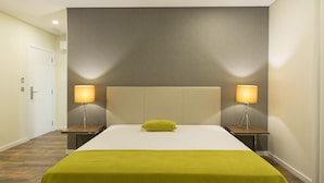 A hotel room with a large bed, two bedside lamps, a pillow, and a wooden nightstand. - Casa Jerónimo B&B (Lamego)