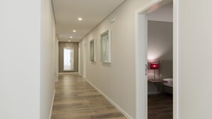 A hallway with wooden flooring, white walls, and framed artwork. - Casa Jerónimo B&B (Lamego)