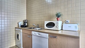 Une cuisine compacte équipée d’un lave-linge, d’un lave-vaisselle, d’un four à micro-ondes, d’une machine à café et d’un grille-pain.