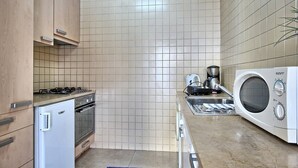 Une cuisine compacte équipée d’une cuisinière à gaz, d’un four, d’un four à micro-ondes et d’une machine à café.