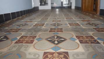 A hallway with patterned floor tiles and a wooden door on the right.