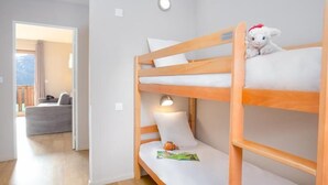 Een stapelbed met een lamp, een pluche knuffel en een boek op het onderste bed.