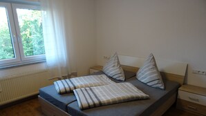 A bedroom with a bed, two bedside tables, a window, and a radiator. - Apartment Bad Rappenau (Bad Rappenau)