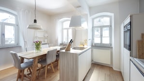 A modern kitchen with a central island, wooden flooring, and large windows. - Ferienhaus Lemon Tree (Rieden)