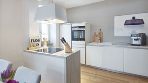 A modern kitchen with a central island, white cabinetry, and a built-in oven. - Ferienhaus Lemon Tree (Rieden)
