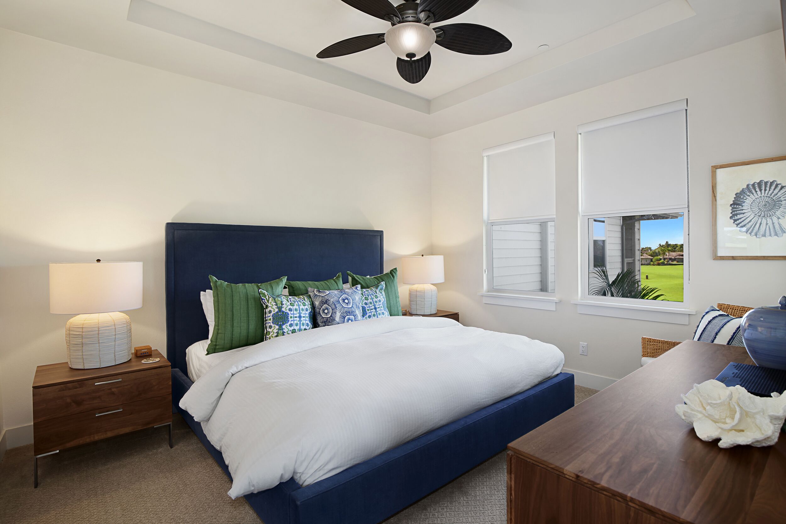 A bedroom with a bed, nightstands, a ceiling fan, and a window with blinds.