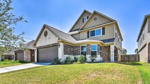 A two-story house with a garage, a brick facade, and a well-maintained lawn. - Spacious Conroe Home - 6 Mi to The Woodlands! (Conroe)