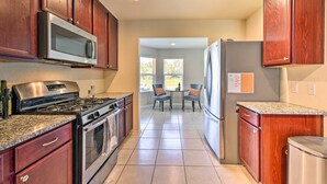 A kitchen with wooden cabinets, stainless steel appliances, granite countertops, and a dining area with chairs. - Spacious Conroe Home - 6 Mi to The Woodlands! (Conroe)