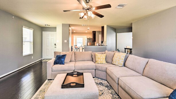 A spacious living room with a large sectional sofa, a ceiling fan, and a kitchen area in the background. - Spacious Conroe Home - 6 Mi to The Woodlands! (Conroe)